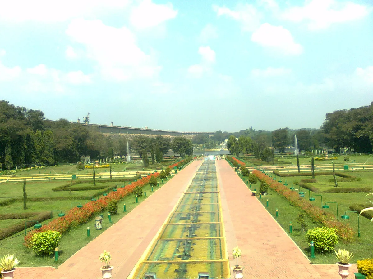 Long paved axis with a central water channel and red bedding lines, KRS dam on the horizon