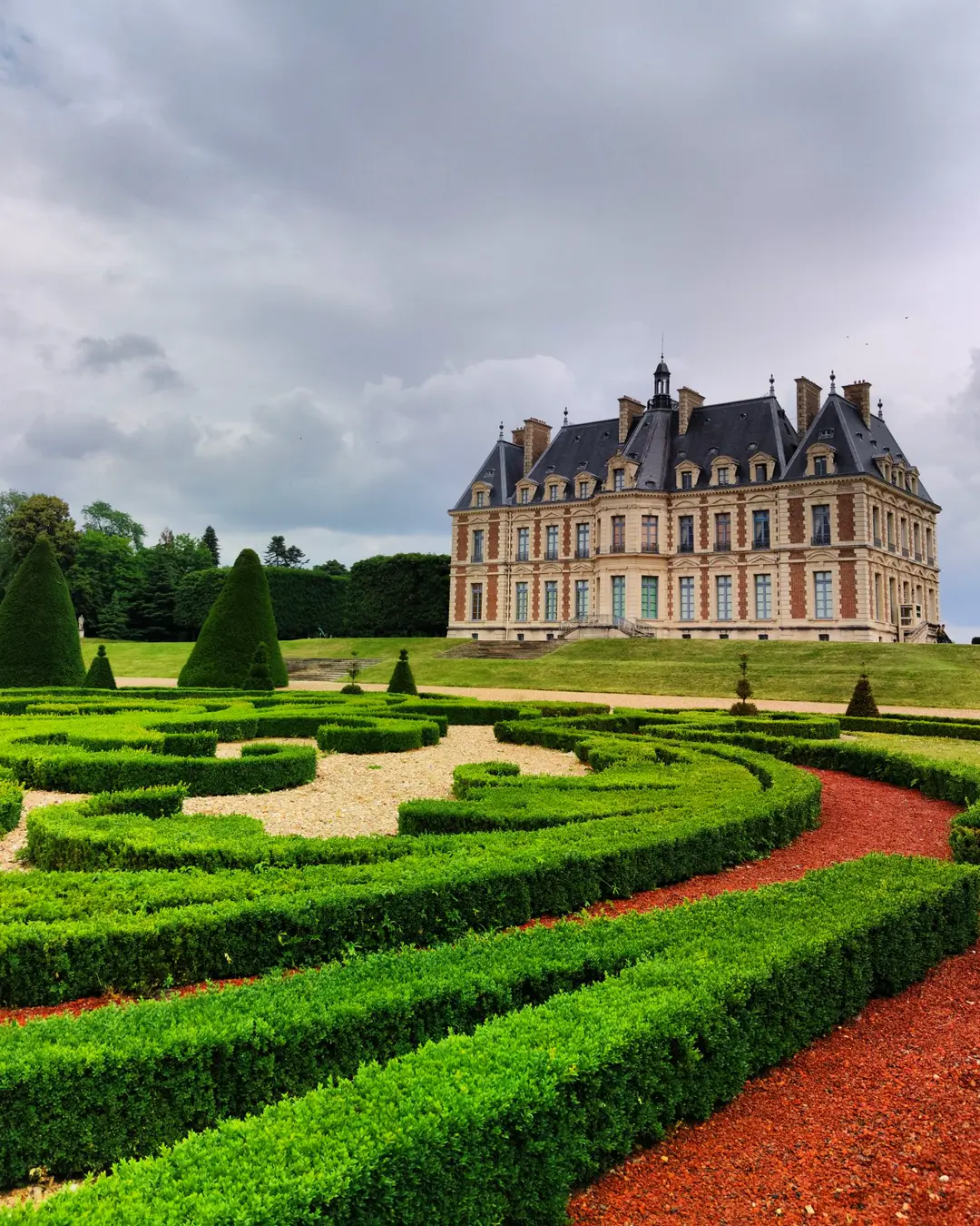 Clipped box parterre in scrolled patterns in front of a large historic house